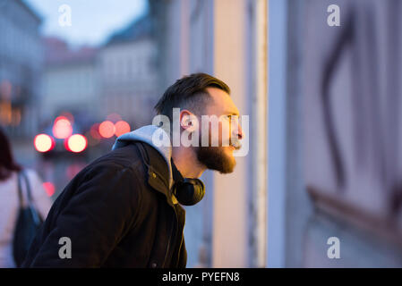 Un bel giovane hipster uomo controllare una vetrina in un ambiente urbano. Foto Stock
