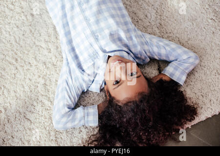 Vista dall'alto di sorridere adorabili african american bambino in pigiama giacente sulla moquette in camera Foto Stock