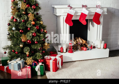 Albero di natale con baubles, confezioni regalo e camino con calze di Natale in camera Foto Stock