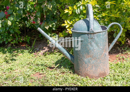Una vista ravvicinata di un vecchio arrugginito metallo verde acqua può nel giardino esterno Foto Stock