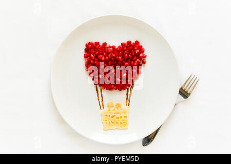 Arte concetto alimentare. Pallone aerostatico con coppia. Frittelle di pizzo con i semi di melograno. Vista dall'alto. Lay piatto. Spazio per la copia Foto Stock