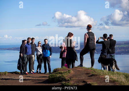 Turisti ed escursionisti di cane su mcarts fort alla sommità della grotta di collina che si affaccia su belfast su una soleggiata domenica mattina, Belfast, Irlanda del Nord Foto Stock
