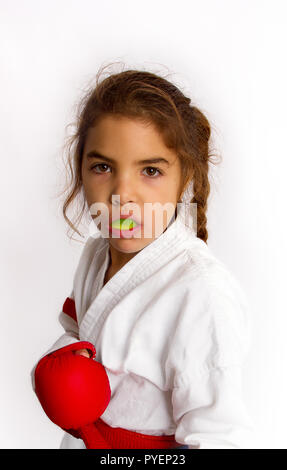 Una bambina karateka in kimono bianco e in un nastro rosso con una mentoniera nella sua labbra dovrebbe essere pronto per la lotta Foto Stock