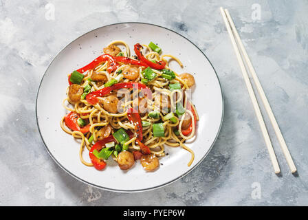 Friggere le tagliatelle con verdure e gamberi su sfondo di calcestruzzo. Foto Stock