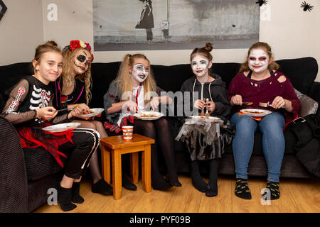 Ottobre 2018 - Gli amici e la famiglia in costume ad una festa di Halloween - gruppo di giovani ragazze a mangiare una merenda di Halloween Foto Stock