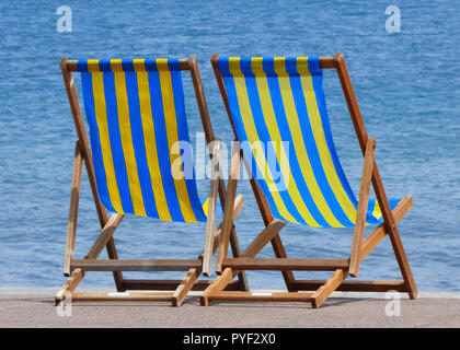 Blu e giallo listati di sedie a sdraio su una spiaggia a Bournemouth Dorset, England, Regno Unito Foto Stock