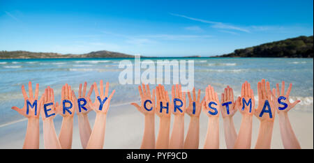 Molte mani la costruzione di parola Buon Natale, la spiaggia e l'oceano Foto Stock