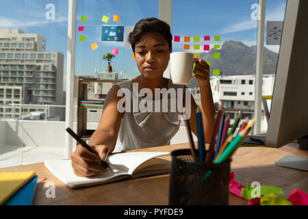 Business executive un caffè mentre la scrittura sul diario Foto Stock