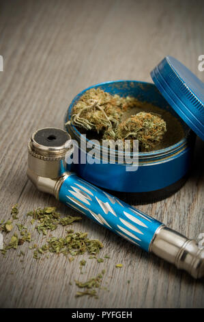 Blu tubo di marijuana e il macinino blu su uno sfondo di legno Foto Stock