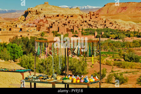 Il Marocco bancarella vendendo collane e ceramiche nella parte anteriore della parete di fango KSAR AIT BENHADDOU con neve sulle montagne Atlas Foto Stock