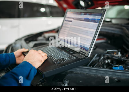 Ingegnere calcolatore rende la diagnostica della vettura in autoservice. Cablaggio del veicolo ispezione Foto Stock