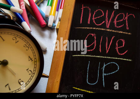 Non mollare mai su una frase colorata manoscritta su lavagna, orologio sveglia con la motivazione e la formazione dei concetti Foto Stock