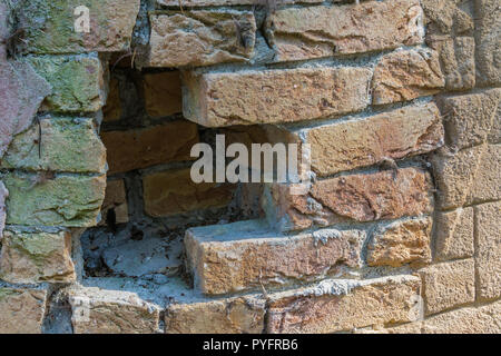 Rosso di un muro di mattoni con un foro aperto in esso texture di sfondo Foto Stock