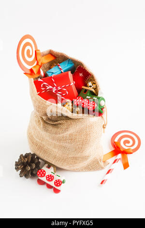 Presenta e giocattoli per Natale nel sacchetto di artigianato su sfondo bianco, colpo verticale Foto Stock