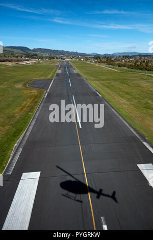 Elicottero ombra sulla pista, l'aeroporto di Rotorua e Lago di Rotorua, Rotorua, Isola del nord, Nuova Zelanda - aerial Foto Stock