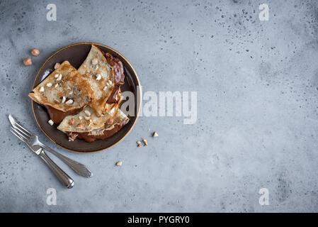 Crepes con diffusione di cioccolato e nocciole. In casa crespelle sottili per la prima colazione o per dessert. Foto Stock