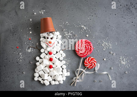 Dolce natalizio pupazzo di neve. Composizione di natale con il rosso e bianco dolci di stagione in forma di uomo di neve su grigio, copia dello spazio. Natale biglietto di auguri, c Foto Stock