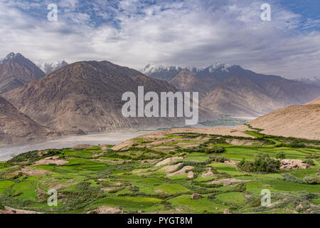 Engels prati di picco sentiero vista di Hindu Kush e green village di Dirch, Langar, Tajik Wakhan, Tagikistan Foto Stock