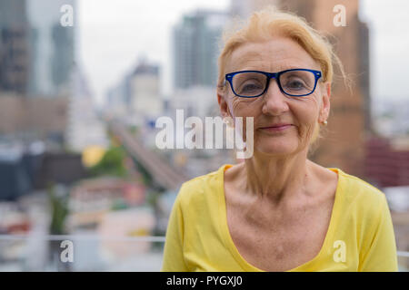 Bella donna senior con gli occhiali in città Foto Stock