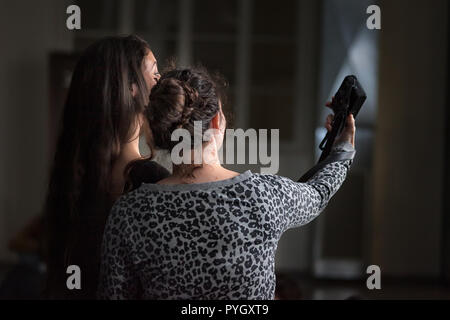 Due giovani ragazze prendendo un selfie con fotocamera digitale indoor, vista posteriore Foto Stock