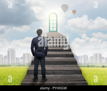 Imprenditore in piedi per camminare su per le scale per la porta sull'erba e cityscape sfondo,il successo aziendale e ambizioni concept Foto Stock