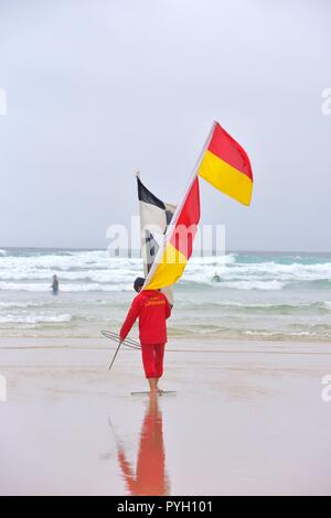 Bagnino RNLI portando sicurezza flag di avviso Foto Stock