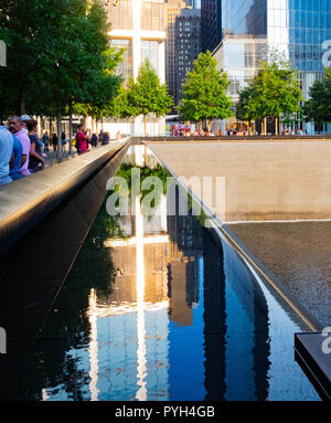 Il sole che splende su un edificio sembra evidenziare una croce alle fontane del World Trade Center Memorial dell'11 settembre a Lower Manhattan, New York City Foto Stock