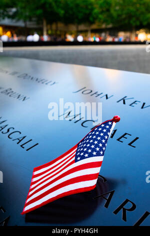 I nomi di alcune delle vittime contrassegnati da una bandiera americana sulla 9/11 World Trade Center Memorial fontane in Lower Manhattan, New York City Foto Stock