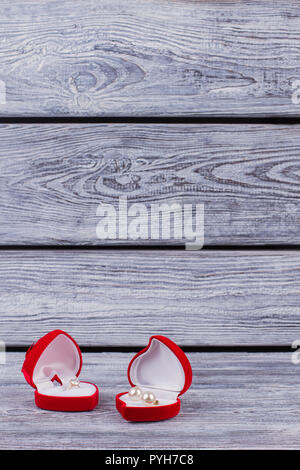 Gioielli a forma di cuore rosso confezioni regalo. Velluto rosso presente di scatole con anello d'oro e orecchini, copia dello spazio. Proposta di matrimonio concetto. Il giorno di San Valentino Foto Stock