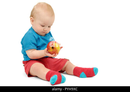 Ragazzino con un Apple seduto su sfondo bianco, isolato Foto Stock