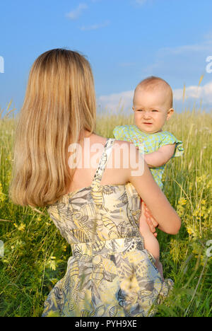 Giovane Donna con bambina sul campo verde, blu cielo in background Foto Stock