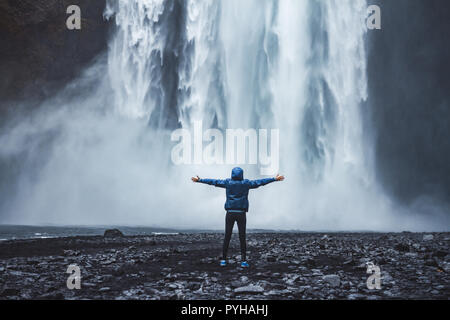 Una persona admirnig la bellezza della Cascata Skogafoss situato in Islanda Foto Stock