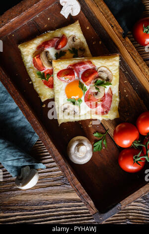 Gustosa pasta sfoglia torte con uova, bacon, funghi e pomodoro Foto Stock