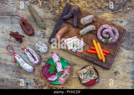 Selezione delle materie francese di salumi di bordo, con foglie di rucola e salsiccia secca su una tavola di legno backgroundi Foto Stock