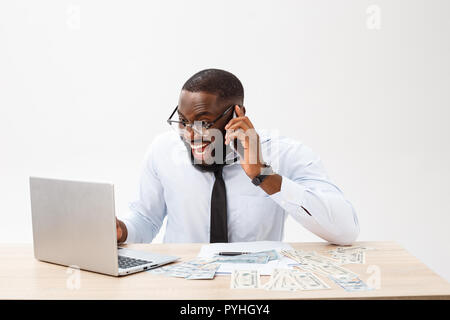 Focalizzato afro-americano di office manager seduto in ufficio con computer portatile, la lettura di documenti importanti con espressione perplessa e tenendo la testa con la mano Foto Stock