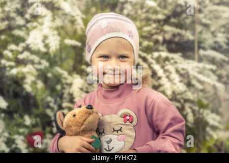 Timido bambino carina ragazza con toy sorridente Ritratto morbido sfondo fiori concetto infanzia felice lifestyle Foto Stock