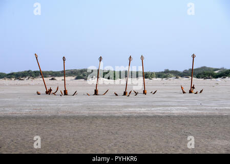 Vecchio arrugginito ancore sulla spiaggia con la bassa marea Foto Stock