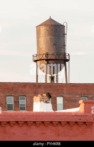 Un arrugginito water tower sollevandosi al di sopra di un vecchio industriale edificio di mattoni a St Louis Foto Stock