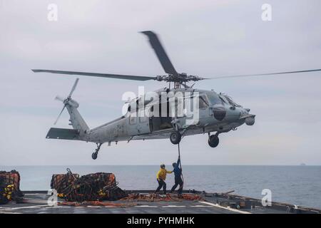 181026-N-XK398-1149 Mar Cinese Orientale (ott. 26, 2018) di Boatswain mate 1. Classe Giacobbe prati, il giallo e il Marinaio Jeff Smith allegare i pallet per un MH-60S Sea Hawk elicottero, assegnato al "Isola Cavalieri del Mare in elicottero Combat Squadron 25, sul ponte di volo dell'amphibious dock landing ship USS Ashland (LSD 48) durante un rifornimento verticale (VERTREP) con la flotta di rifornimento USNS oliatore Tippecanoe (T-AO 199). Ashland, parte della Vespa Anfibia Gruppo pronto, è operativo nell'Indo-Pacifico regione per migliorare l'interoperabilità con i partner e servire come una pronta risposta in vigore per qualsiasi Foto Stock