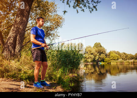 Giovane uomo di pesca sul fiume. Fisherman godendo di hobby. La filatura. Uno stile di vita attivo Foto Stock
