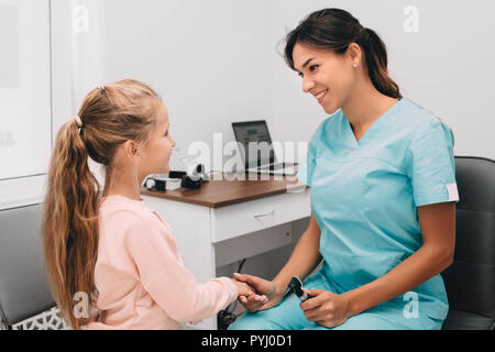 Pediatra scuotendo leggermente la mano della bambina in office Foto Stock