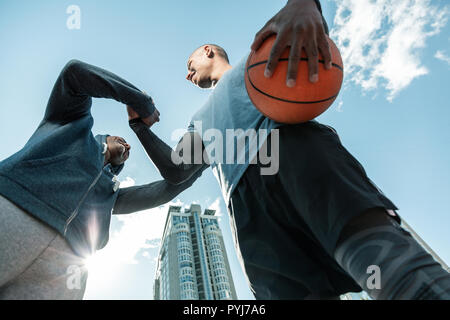 Basso angolo di un bel giovane uomo tenendo una palla Foto Stock