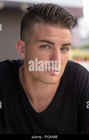 Volto del giovane uomo bello seduti all'aperto Foto Stock