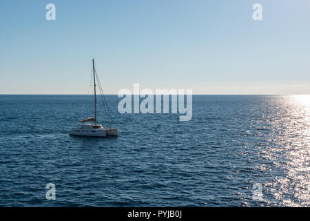 Bianco in barca a vela in Malta viaggio a Gozo su un luminoso giorno di estate nel bel mezzo del nulla. catamarano a vela barca. no vele fino in mare calmo. Foto Stock