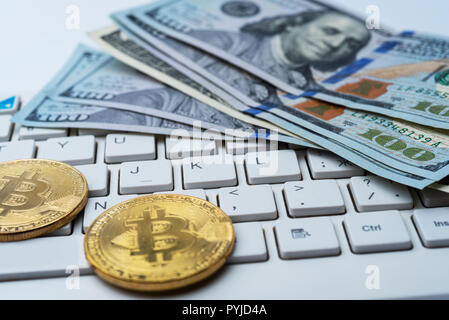 Bitcoin moneta con tastiera e Dollari USA. Bitcoin monete d'oro sul dollaro banconote ufficio con uno sfondo bianco. Cryptocurrency digitale. Le monete metalliche Foto Stock