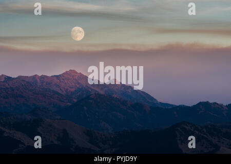 La luna sorge sopra le montagne circostanti Jackson Wyoming come il sole tramonta sotto Teton Pass. Foto Stock