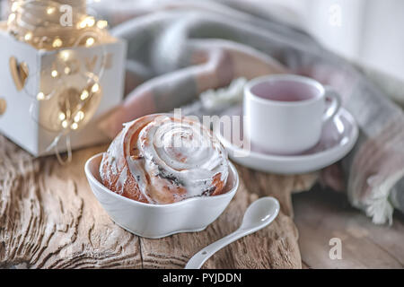 Deliziosi dolci fatti in casa panini alla cannella e zucchero a velo il Natale al vecchio tavolo di legno. Svedese tradizionale pasticceria, kanelbullar. Foto Stock