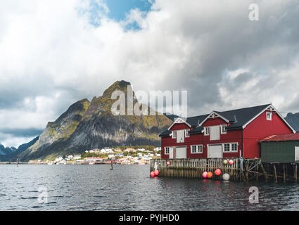 Famosa attrazione turistica di Reine in Lofoten, Norvegia con red rorbu case, nuvole, Rainy day con ponte e di erba e fiori. Foto scattata in Norwa Foto Stock