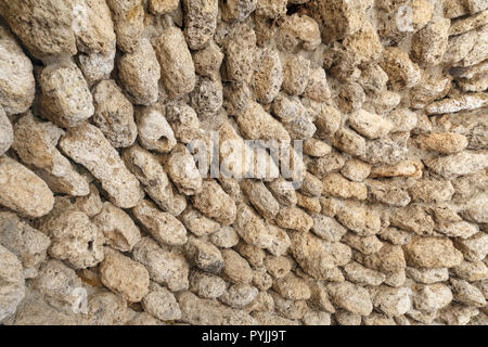 Antiche mura fatte di pietre rotonde come sfondo o uno sfondo Foto Stock