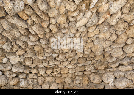 Antiche mura fatte di pietre rotonde come sfondo o uno sfondo Foto Stock